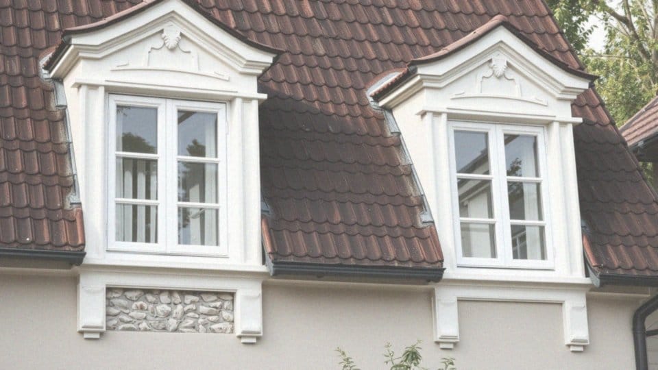 Jakie dekoracje elewacyjne można zastosować przy białych oknach i brązowym dachu?